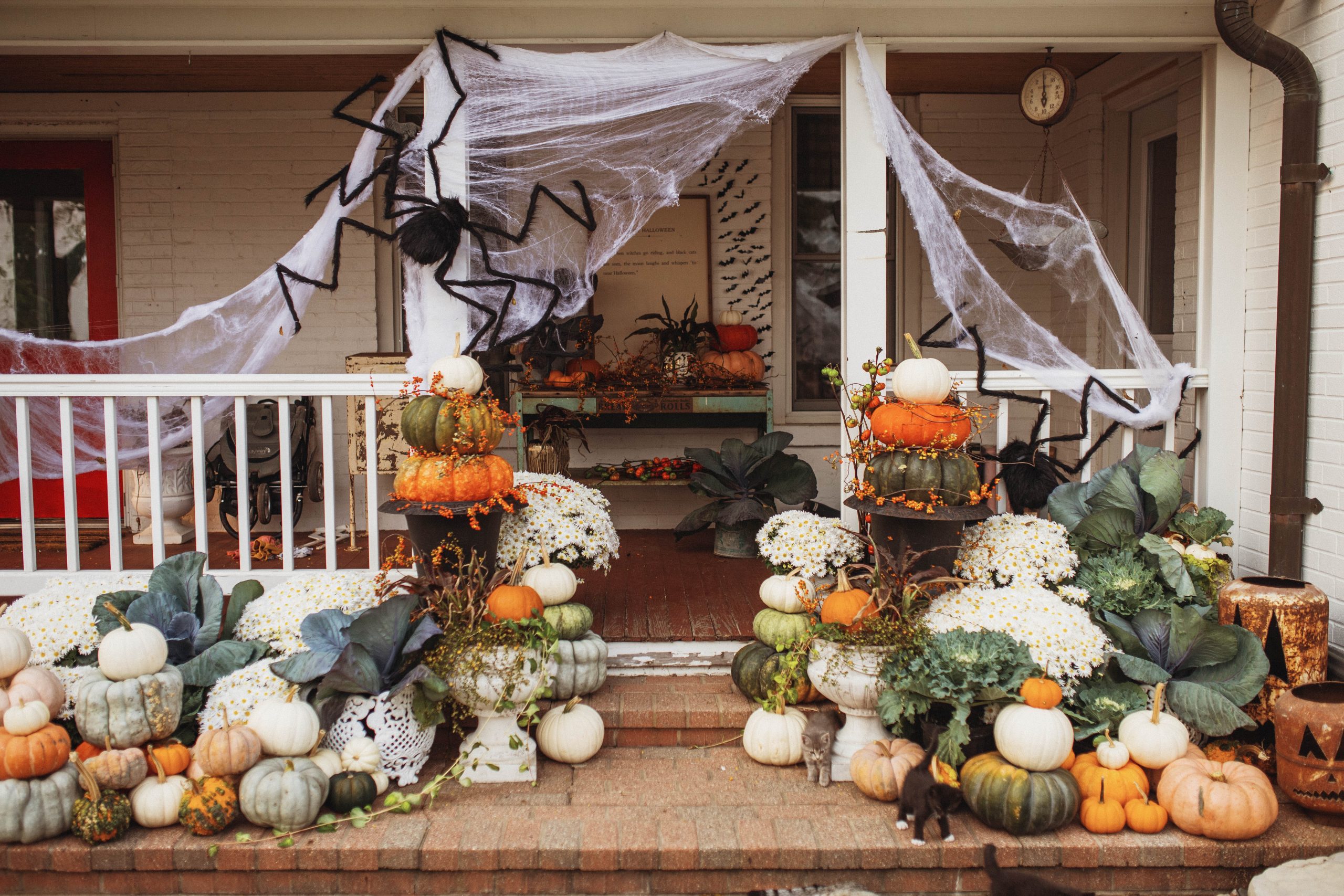 Farmhouse Fall Front Porch with spider webs pumpkins mums and large fake spider