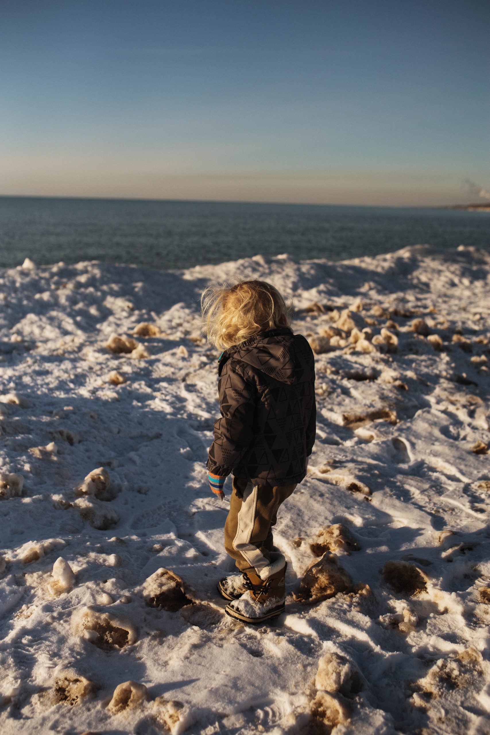 Toddler looking over the ice balls of lake michigan